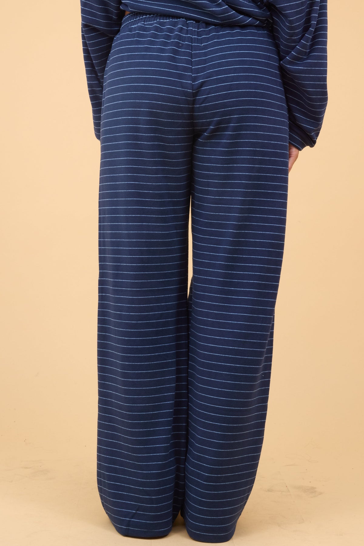 Back view of a woman wearing a navy stripe, wide leg lounge pant.