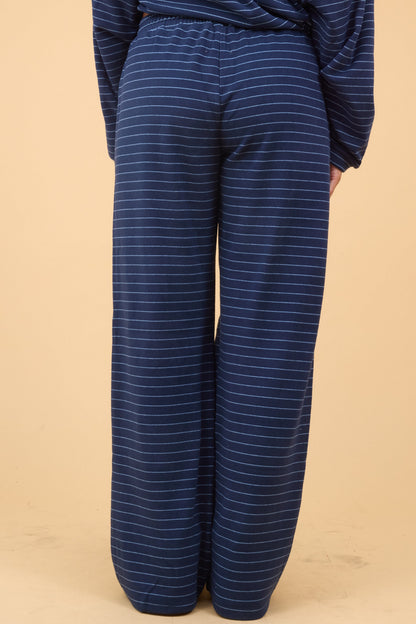 Back view of a woman wearing a navy stripe, wide leg lounge pant.