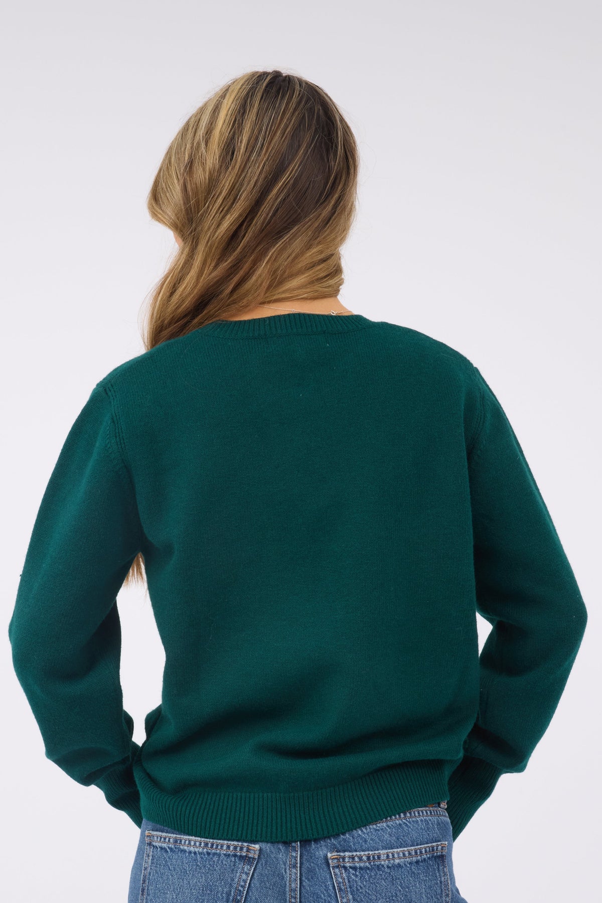 Back view of ayoung woman wearing a green long sleeve sweater with a ribbed waist.