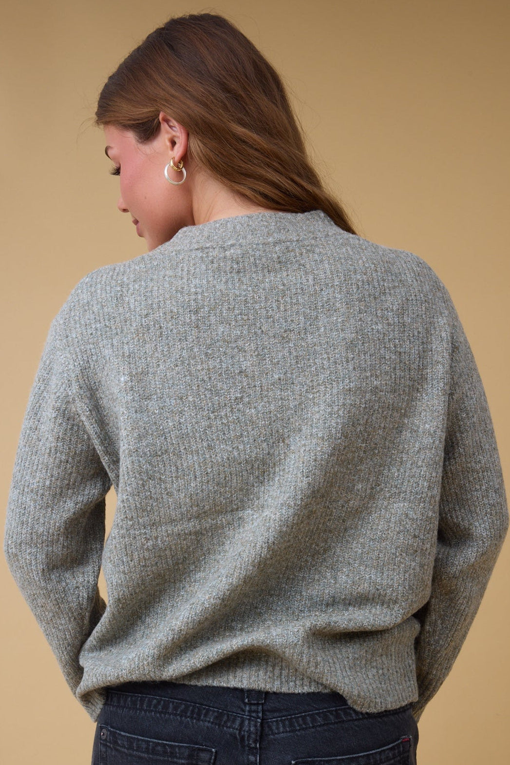 Back view of a woman wearing a green rib knit pullover sweater.