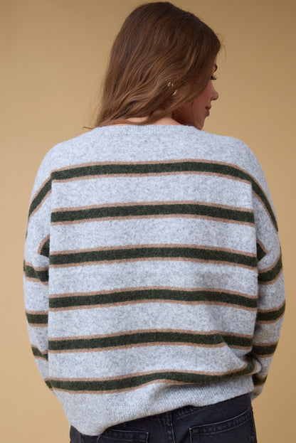 Back view of a woman wearing a loose stripe sweater in grey with green &gold stripes.