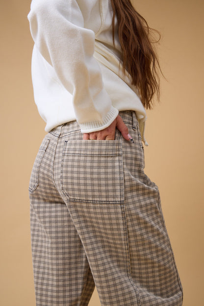 Close view of a woman wearing brown plaid check pant.