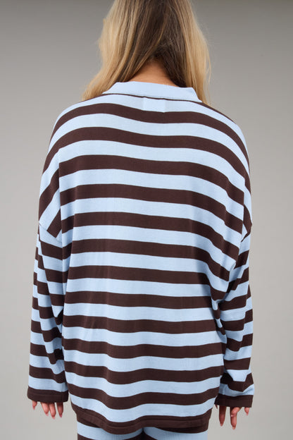 Back view of a woman wearing a a loose fitting brown & light blue top.