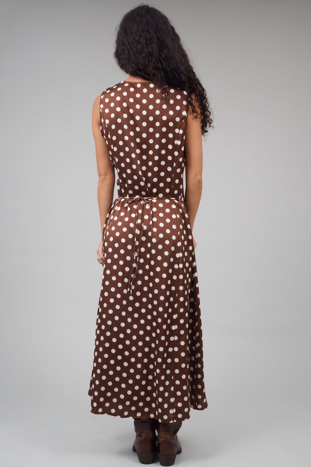 Back view of a woman wearing a brown & cream polka dot midi-maxi dress.