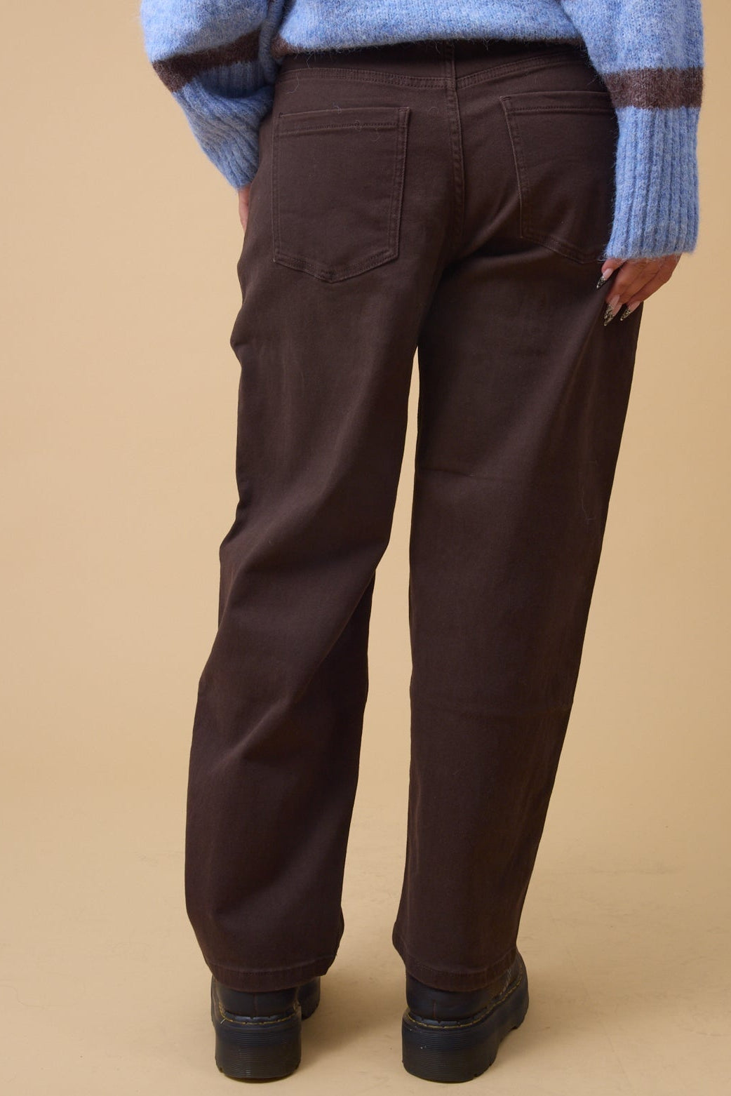 Back view of a woman wearing loose fitting, wide leg pants iwth back pockets.