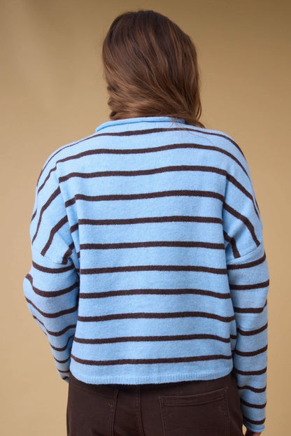 Back view of a woman wearing a light blue & brown stripe loose fitting cardigan with long sleeves.
