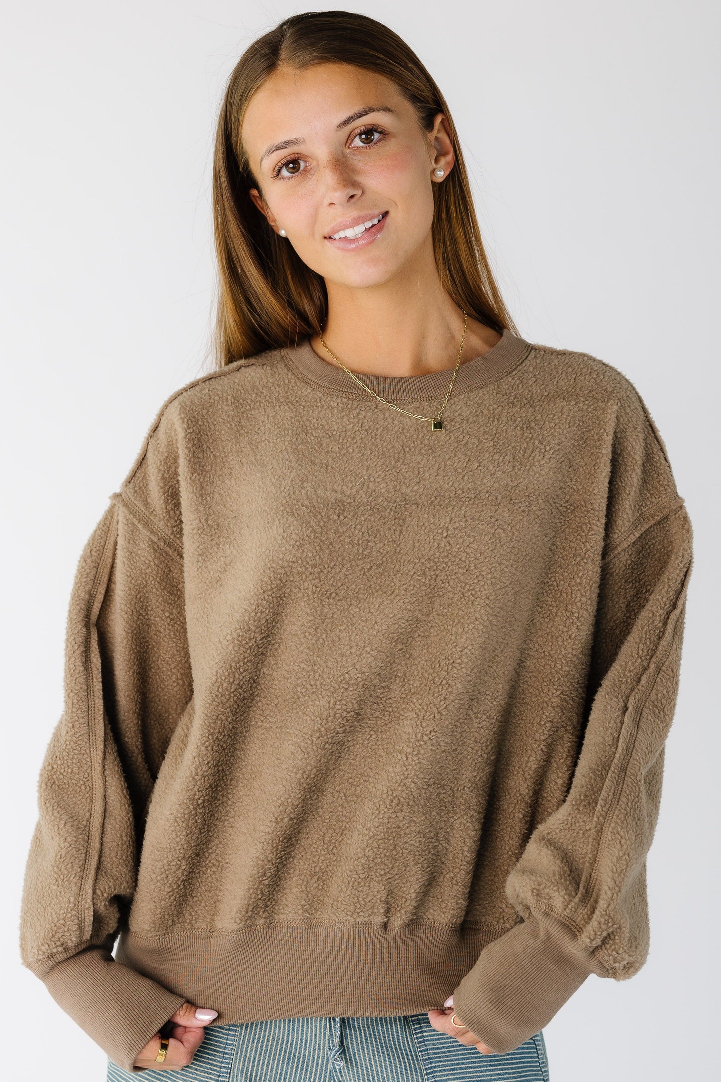 Woman wearing a brown reversible sweatshirt-sweater with wide ribbing at cuffs and waist