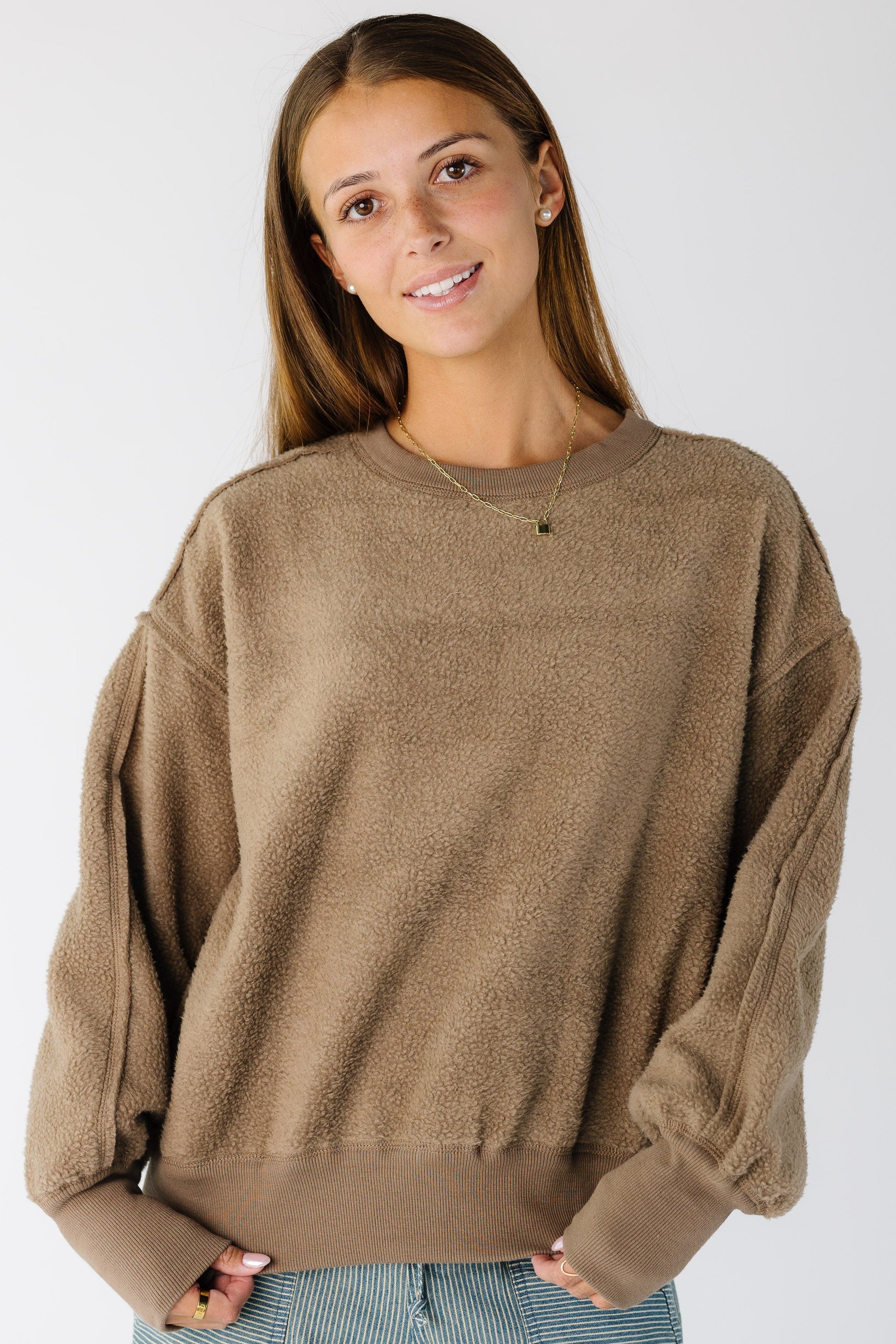 Woman wearing a brown reversible sweatshirt-sweater with wide ribbing at cuffs and waist
