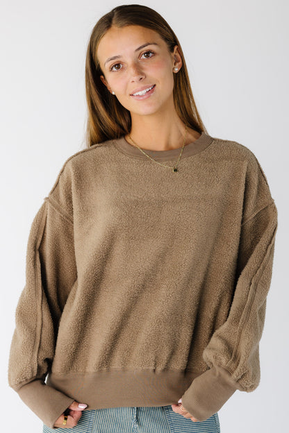 Woman wearing a brown reversible sweatshirt-sweater with wide ribbing at cuffs and waist