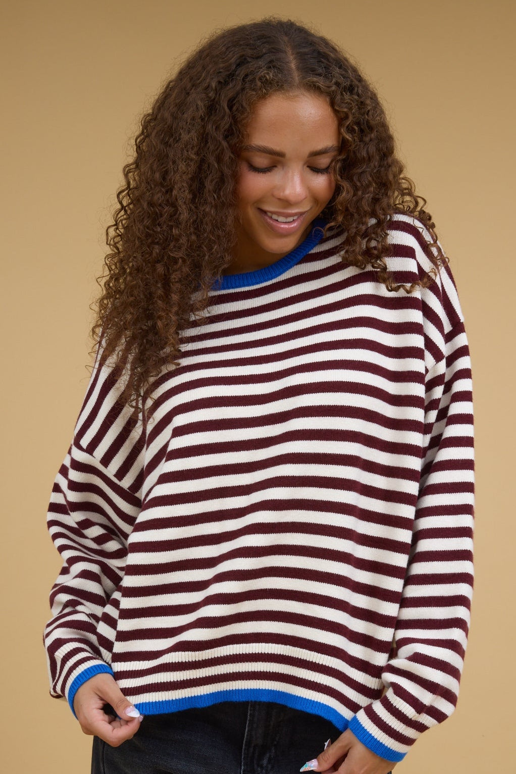 Teenage girl earing a burgundy & cream stripe top with long sleeves and a blue crew neckline, and blue sleeve cuffs.