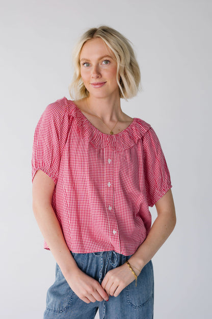 Young woman a wearing a red & white gingham button down blouse with short puff sleeves and a round ruffle collar.