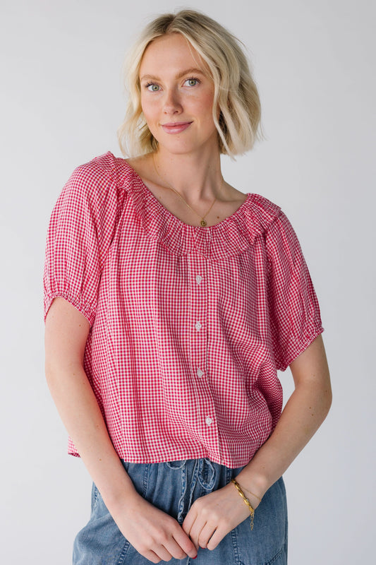 Young woman a wearing a red & white gingham button down blouse with short puff sleeves and a round ruffle collar.