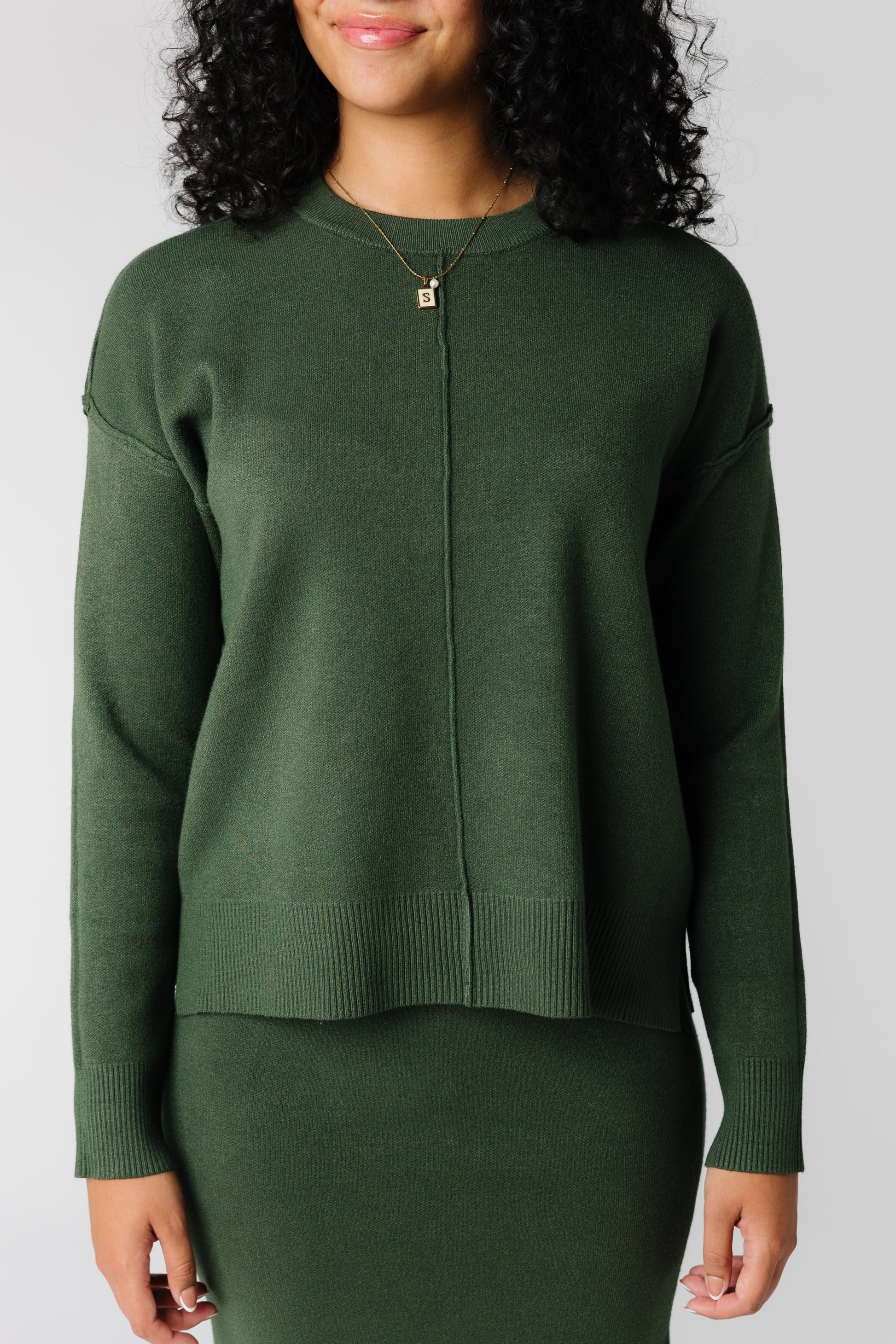 Close view of dark green crew neck sweater with long sleeves