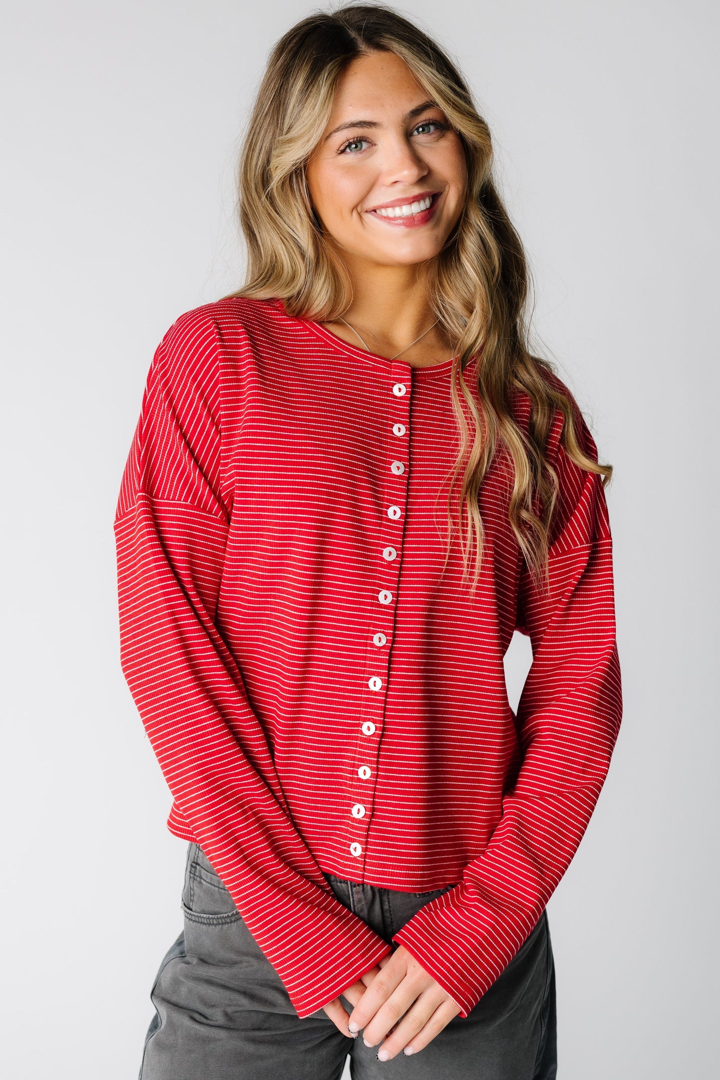 Woman wearing a red pinstripe cardigan with long sleeves and round neckline