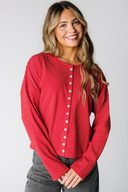 Woman wearing a red pinstripe cardigan with long sleeves and round neckline