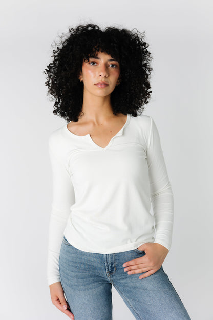 White rib knit top with close fitting long sleeves and notched neckline