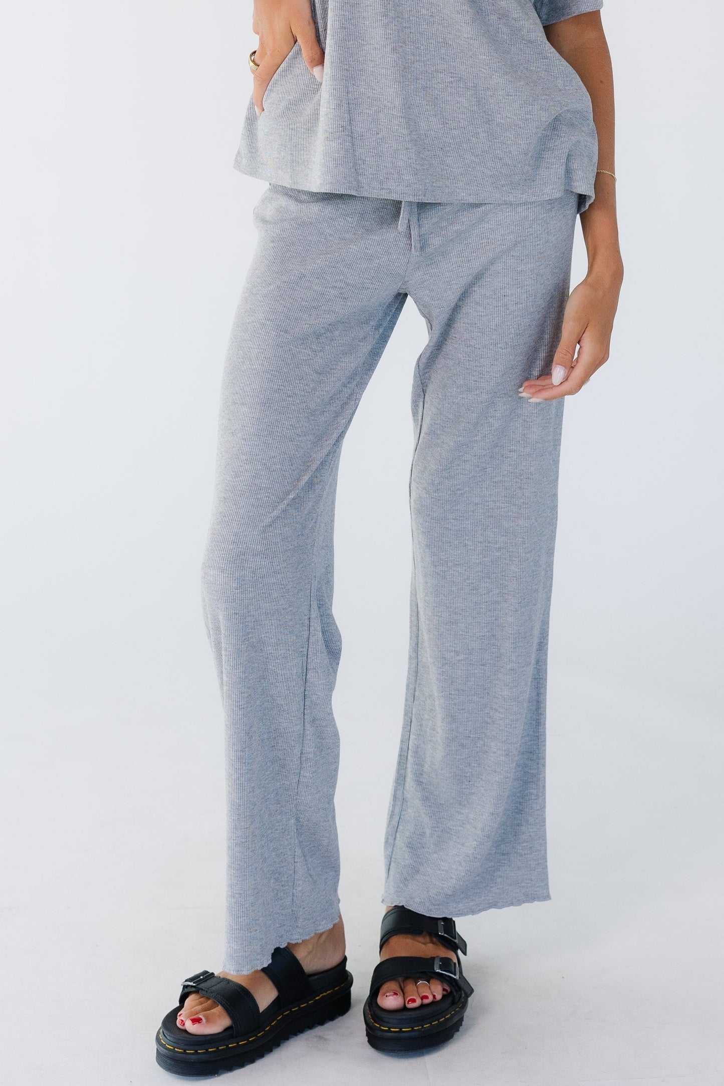 Young woman wearing a modest pair of rib knit lounge pants with a wide cut leg in light grey.