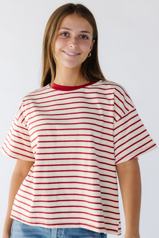 Young woman wearing a cream and red stripe tee with a red crew neckline and short sleeves.