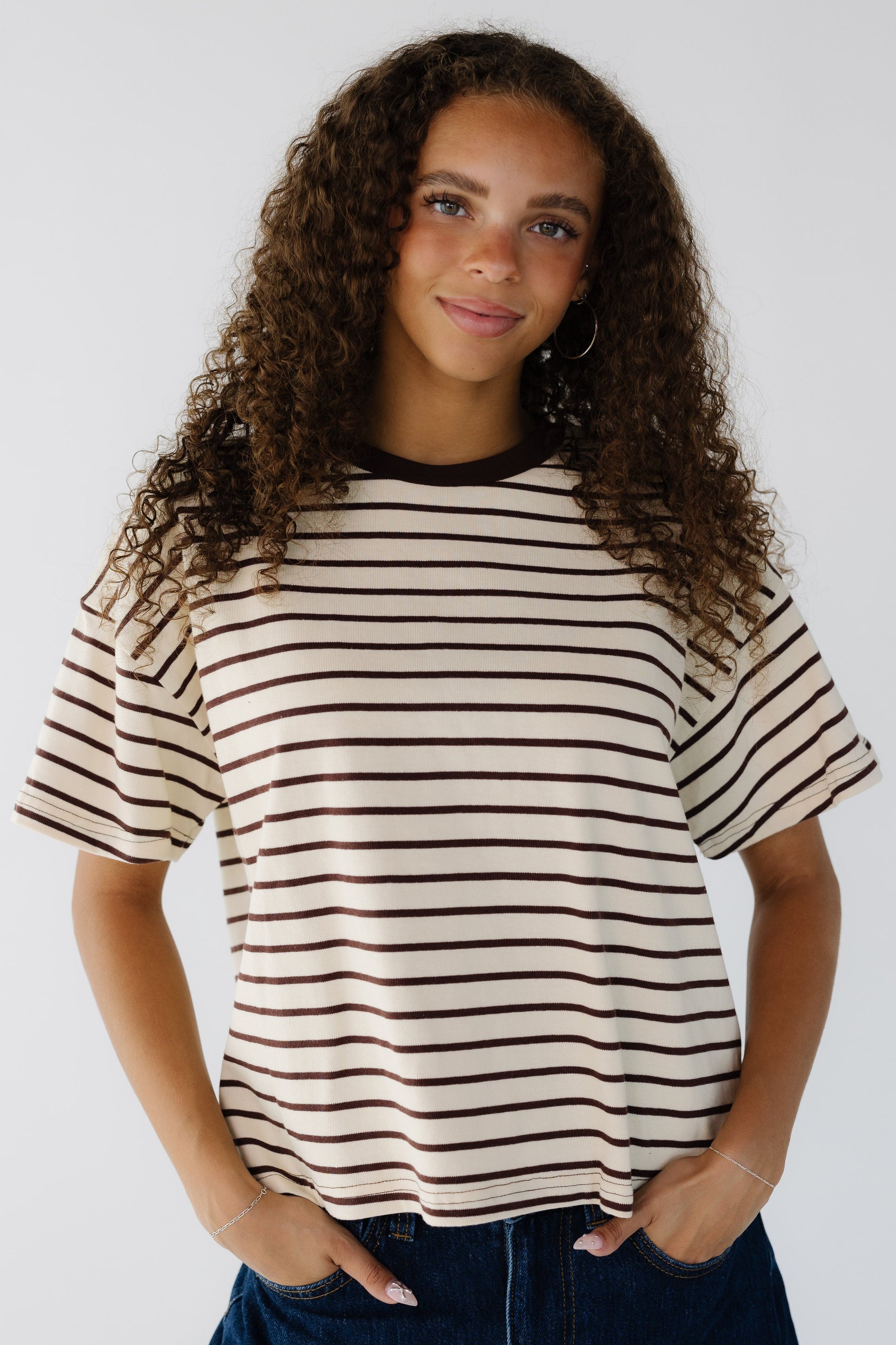 Young woman wearing a modest cream & brown stripe short sleeve tee with a crew neckline.