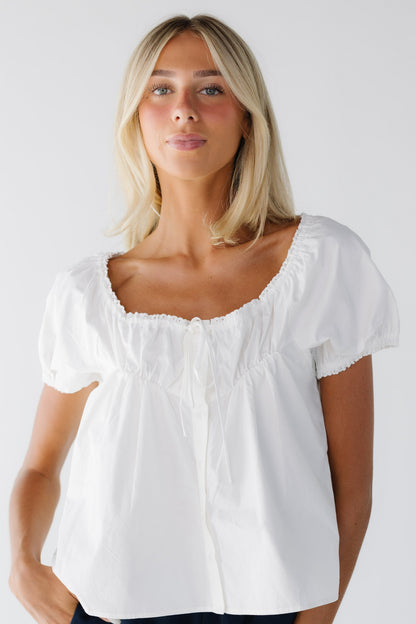 Young woman wearing a modest loose fitting ,button down blouse in white with a wide ruffled neckline with short puff sleeves.