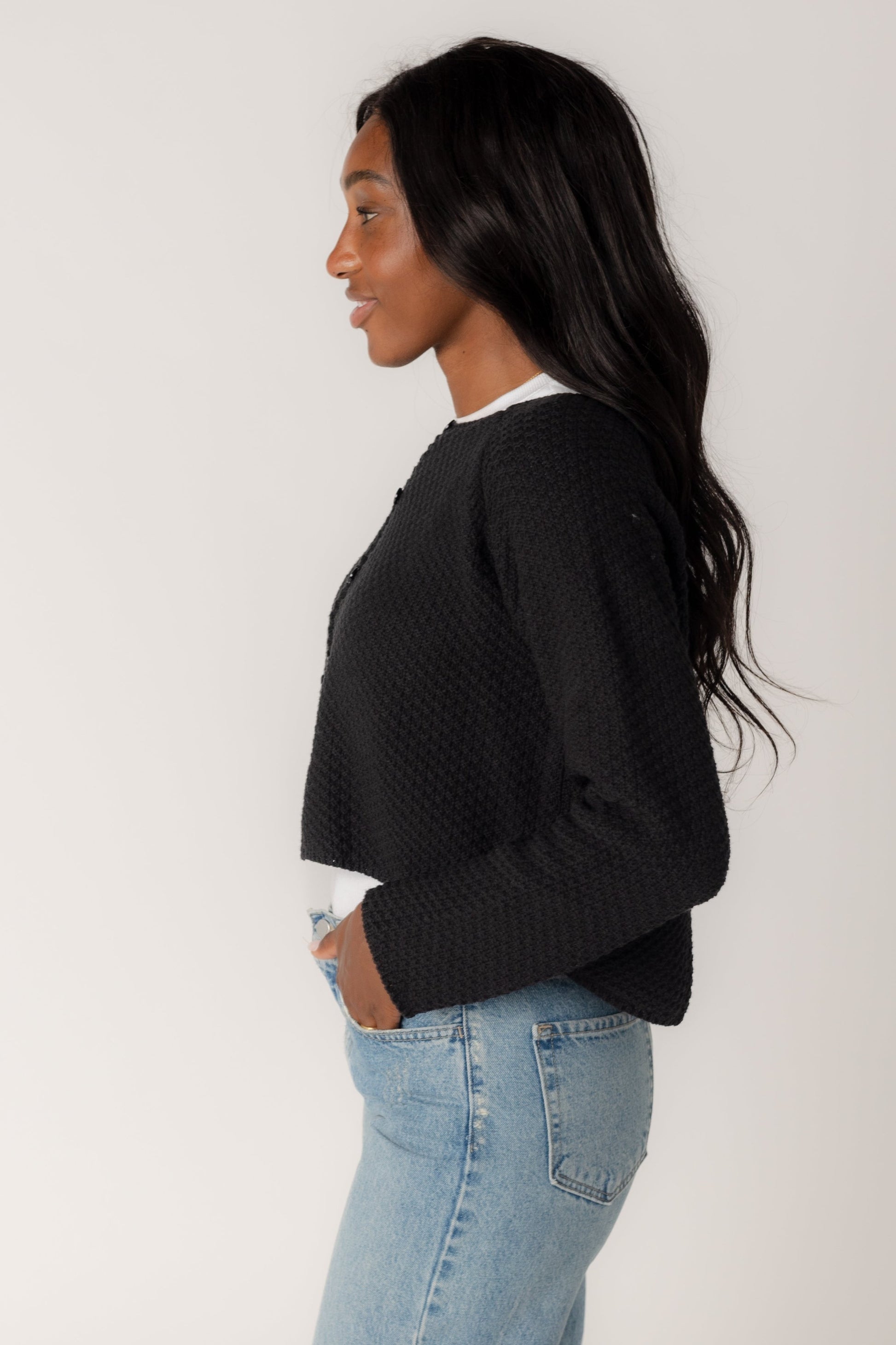 Side view of long sleeve black cardigan with round neckline