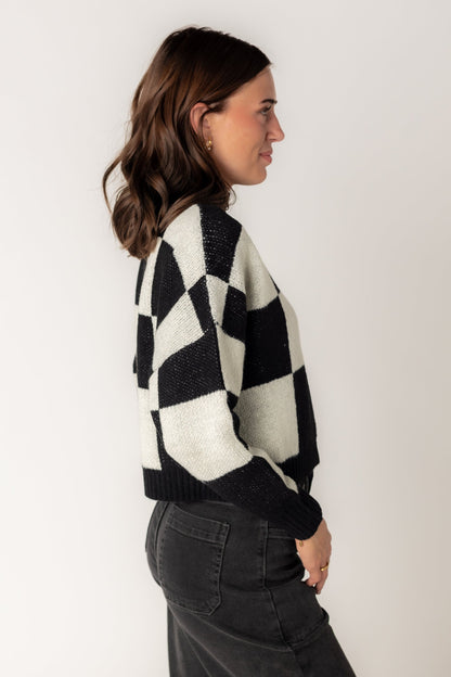 Side view of large checkered  sweater with long sleeves and mock turtle neck