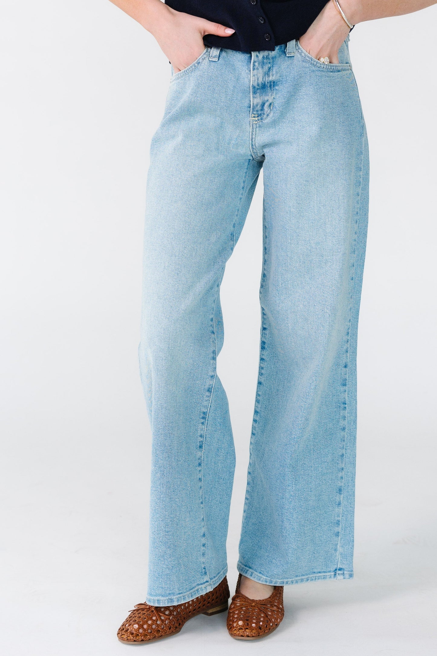 Woman wearing mid-rise jeans with wide cut legs in light denim.