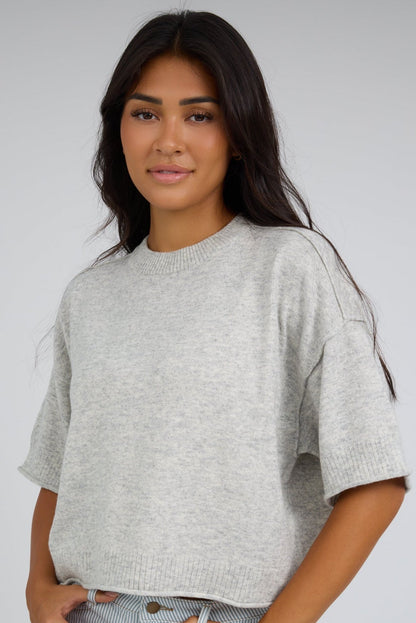 Young woman wearing a modest  heather grey loose fitting sweater with elbow length sleeves and w wide ribbed crew neckline.