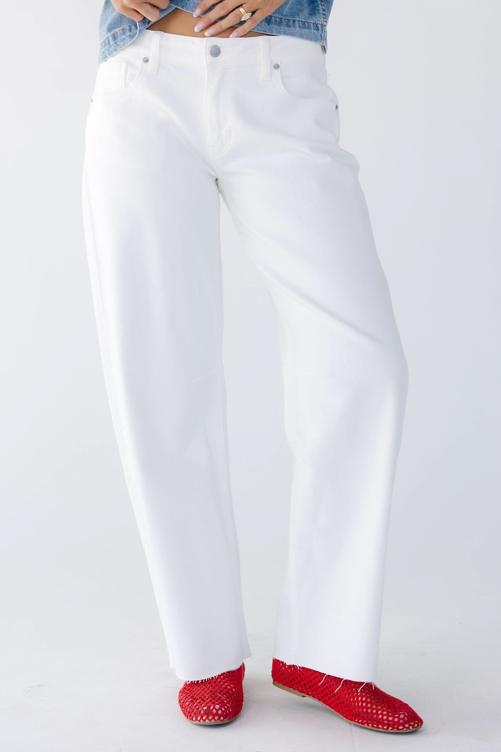 Young women wearing modest white barrel jeans with wide cut legs and scissor cut hems.