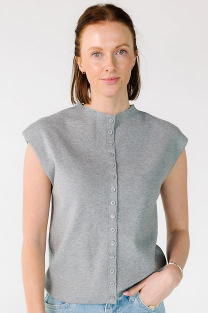 Young woman wearing a modest, sleeveless,  button down cardigan in heather grey.