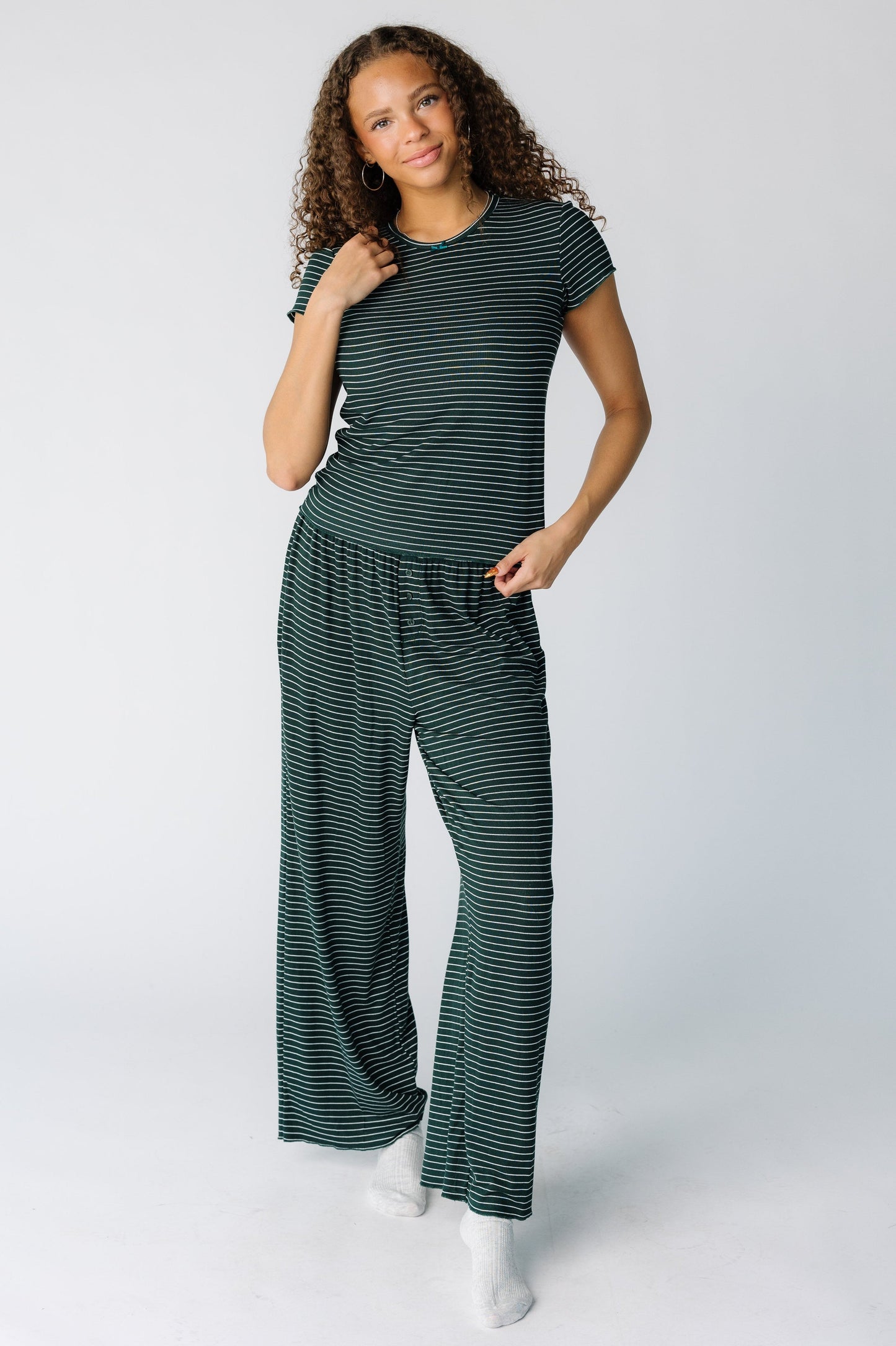 Woman wearing a modest green stripe pajama 2 piece set with short sleeves and long length leg