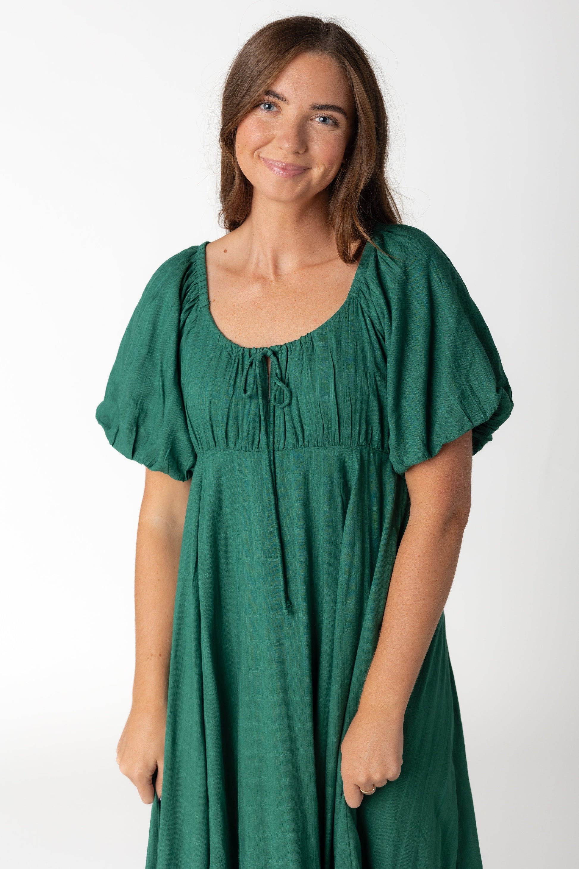 Close view of emerald green midi dress with textured stripe details with full skirt