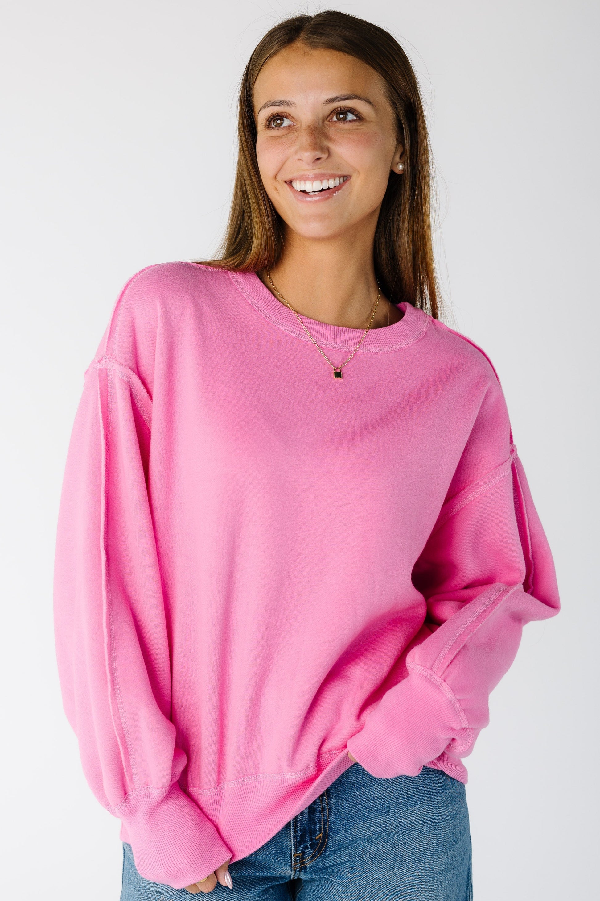 Woman wearing a modest pink sweatshirt with crew neckline and long sleeves