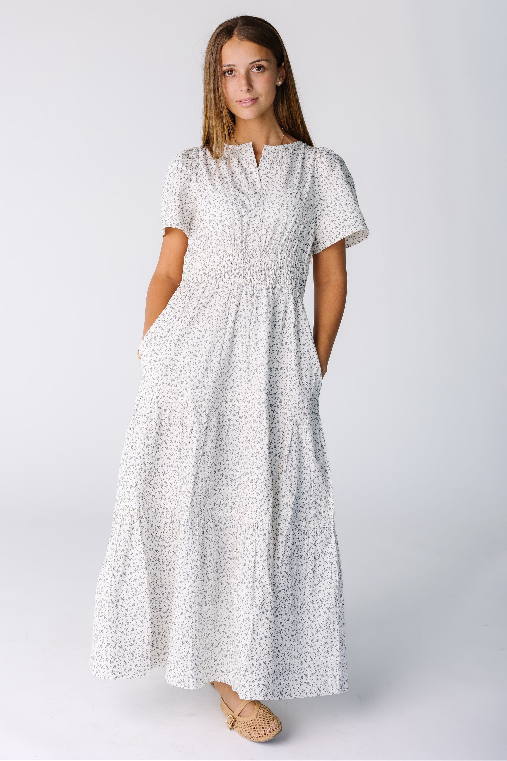 Woman wearing a midi-maxi dress in white floral print with short sleeves and wide elastic waist