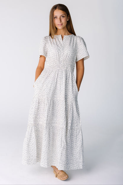 Woman wearing a midi-maxi dress in white floral print with short sleeves and wide elastic waist