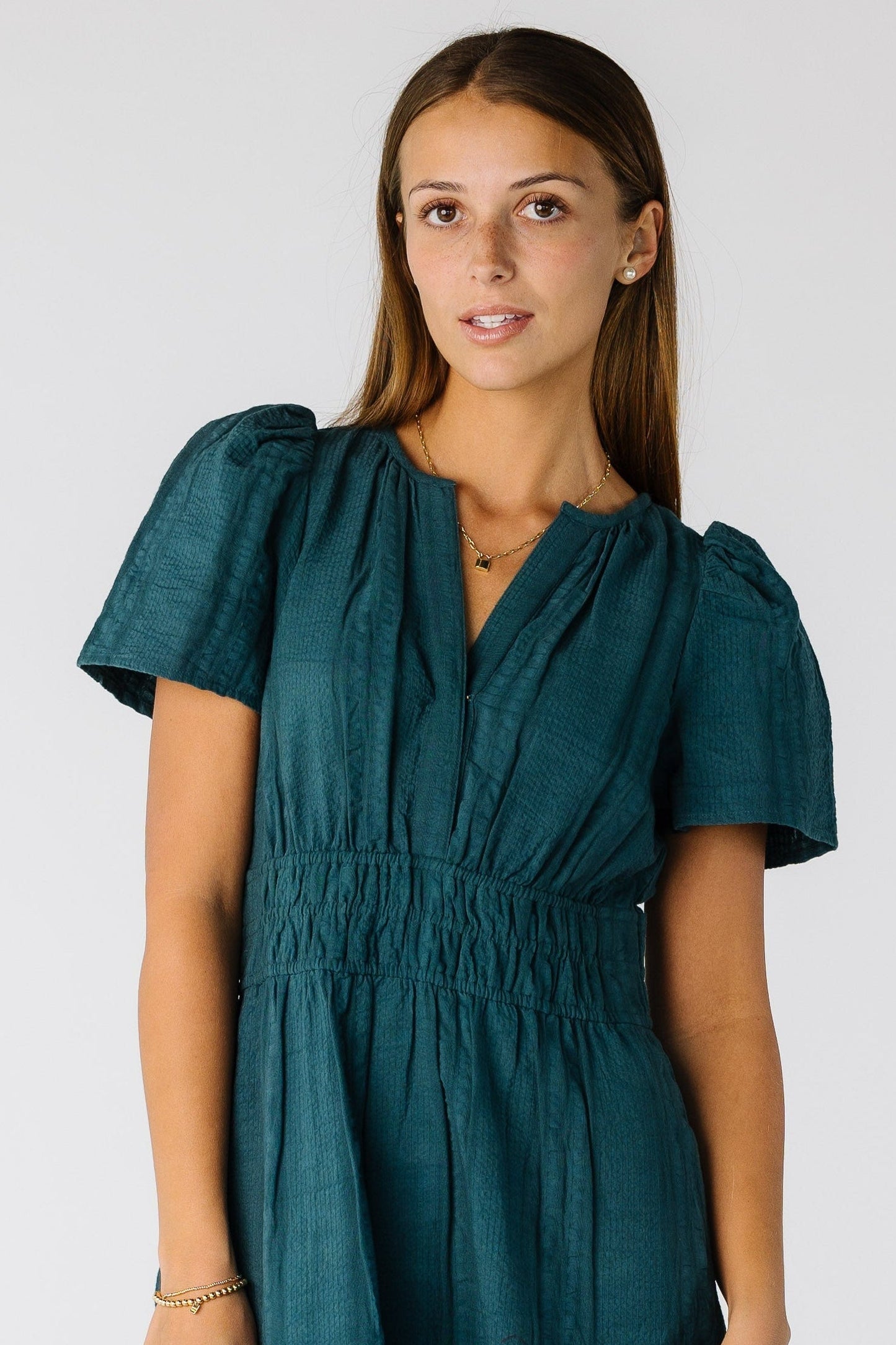 Close view of a woman wearing a teel dress with short sleeves and V-neckline