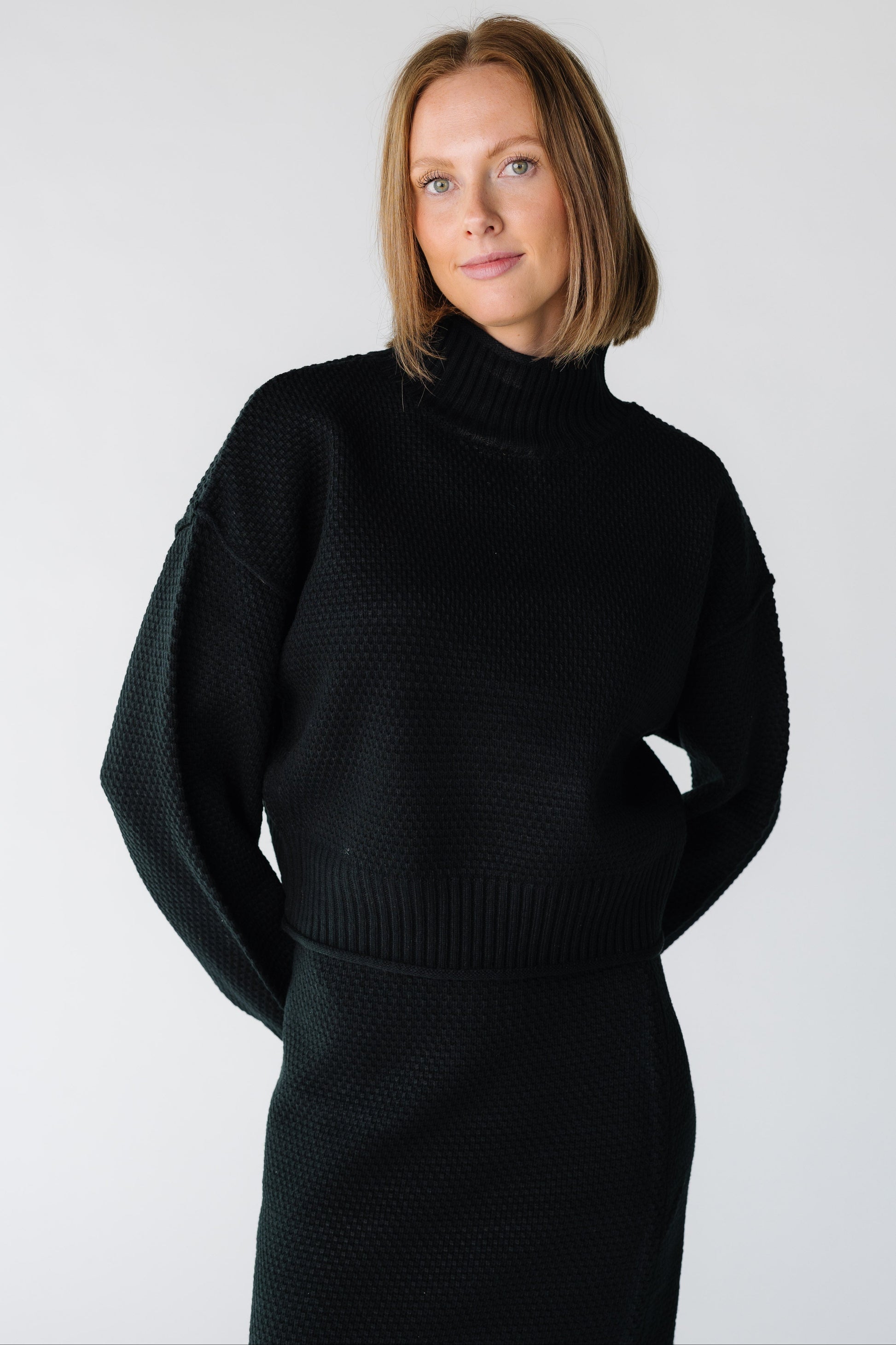 Close view of a woman wearing a black textured sweater and skirt set