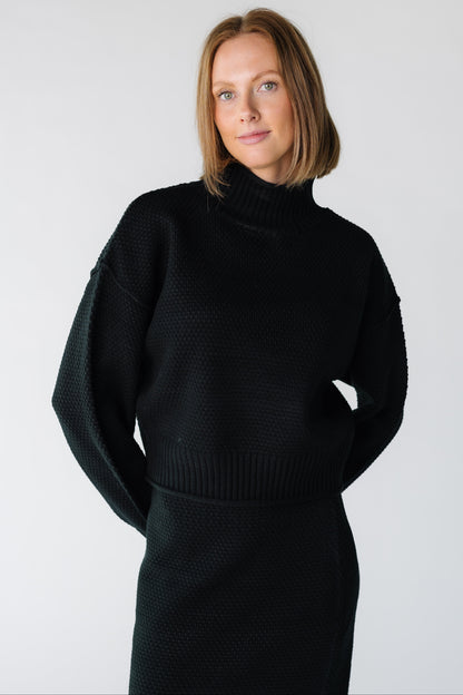 Close view of a woman wearing a black textured sweater and skirt set