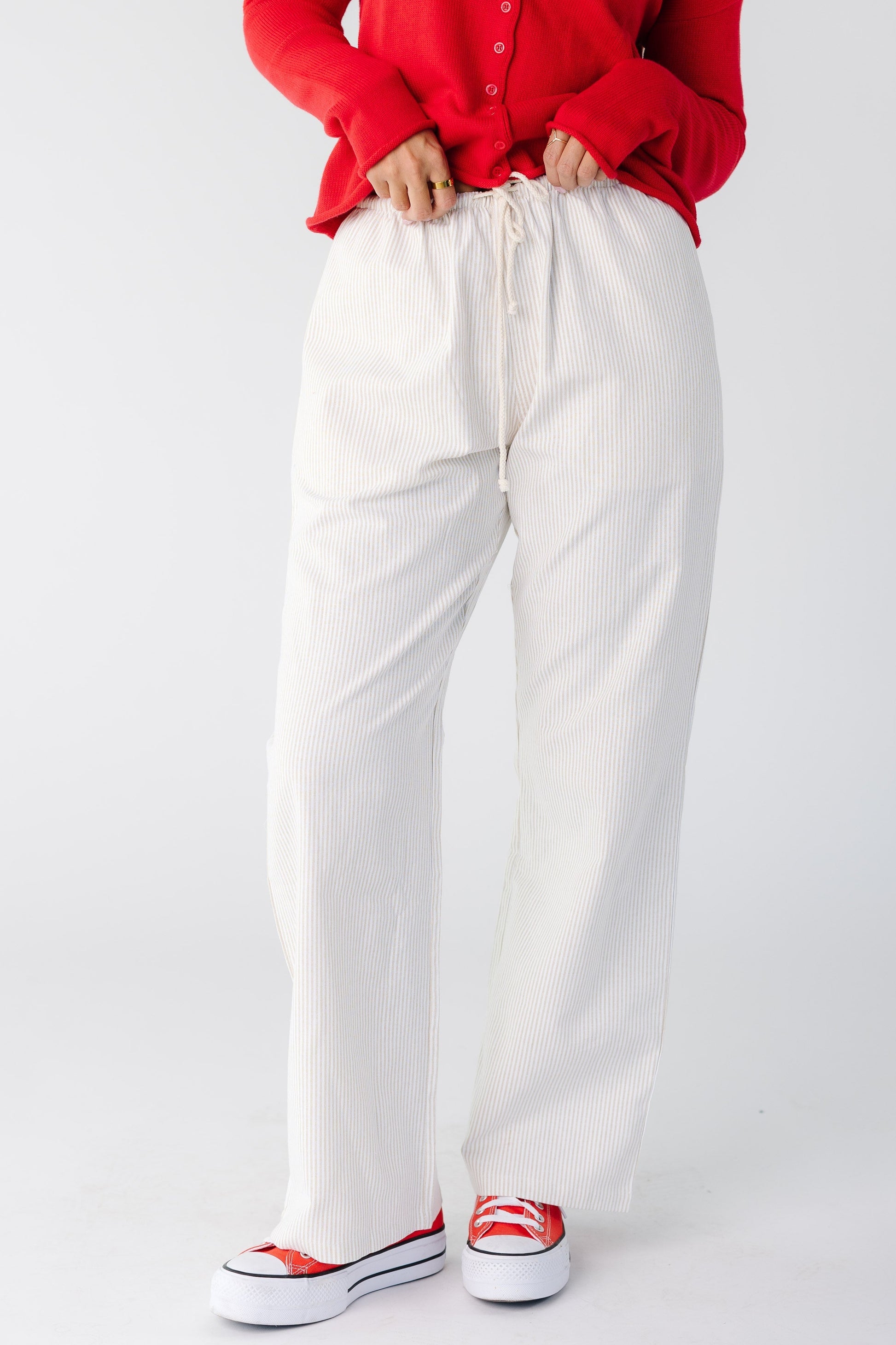Woman wearing a pair of taupe and white stripe woven pant with drawstring waist