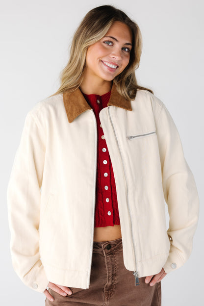Woman wearing a cream color denim jacket with brown corduroy collar