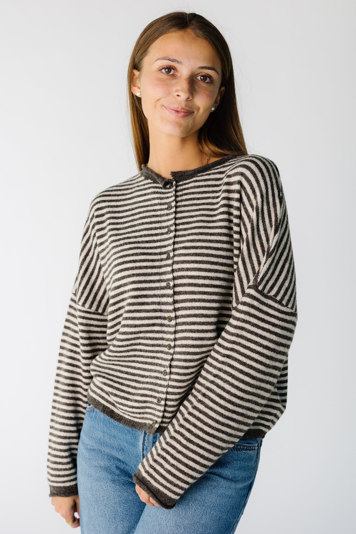 Woman wearing a brown and cream stripe button down cardigan with long sleeves and rolled neckline