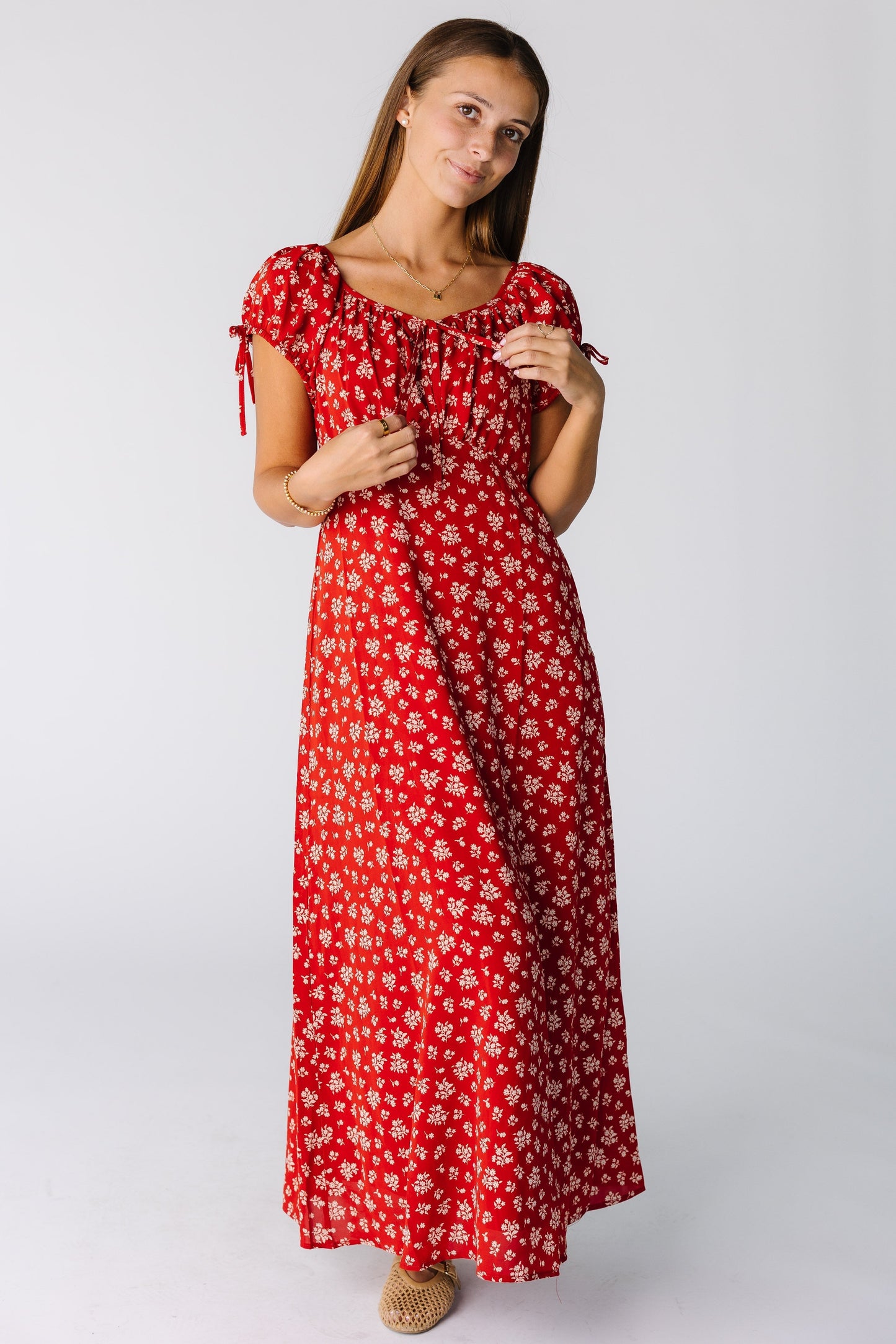 Woman wearing a modest red print maxi-midi dress with a scoop neckline, short and empire waist