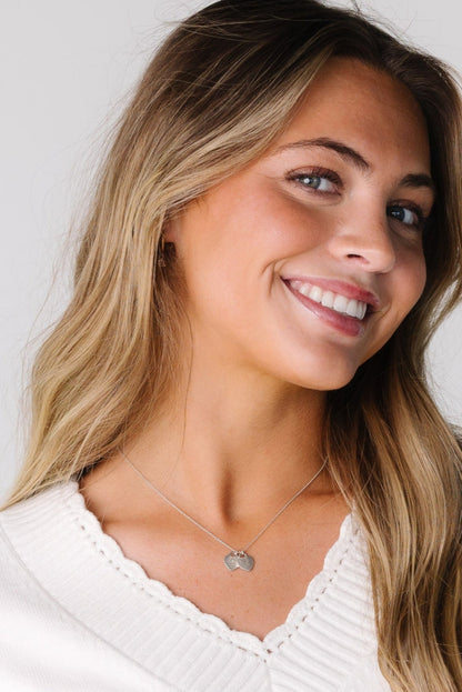 Close view of a woman wearing an off white sweater with a scallop edge.