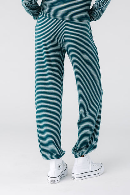 Back view of a woman wearing a pair of green and cream stripe lounge pants