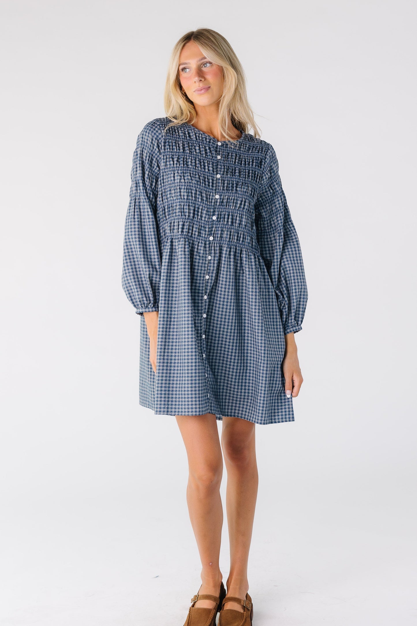 Woman wearing a blue gingham button down dresss with long sleeves