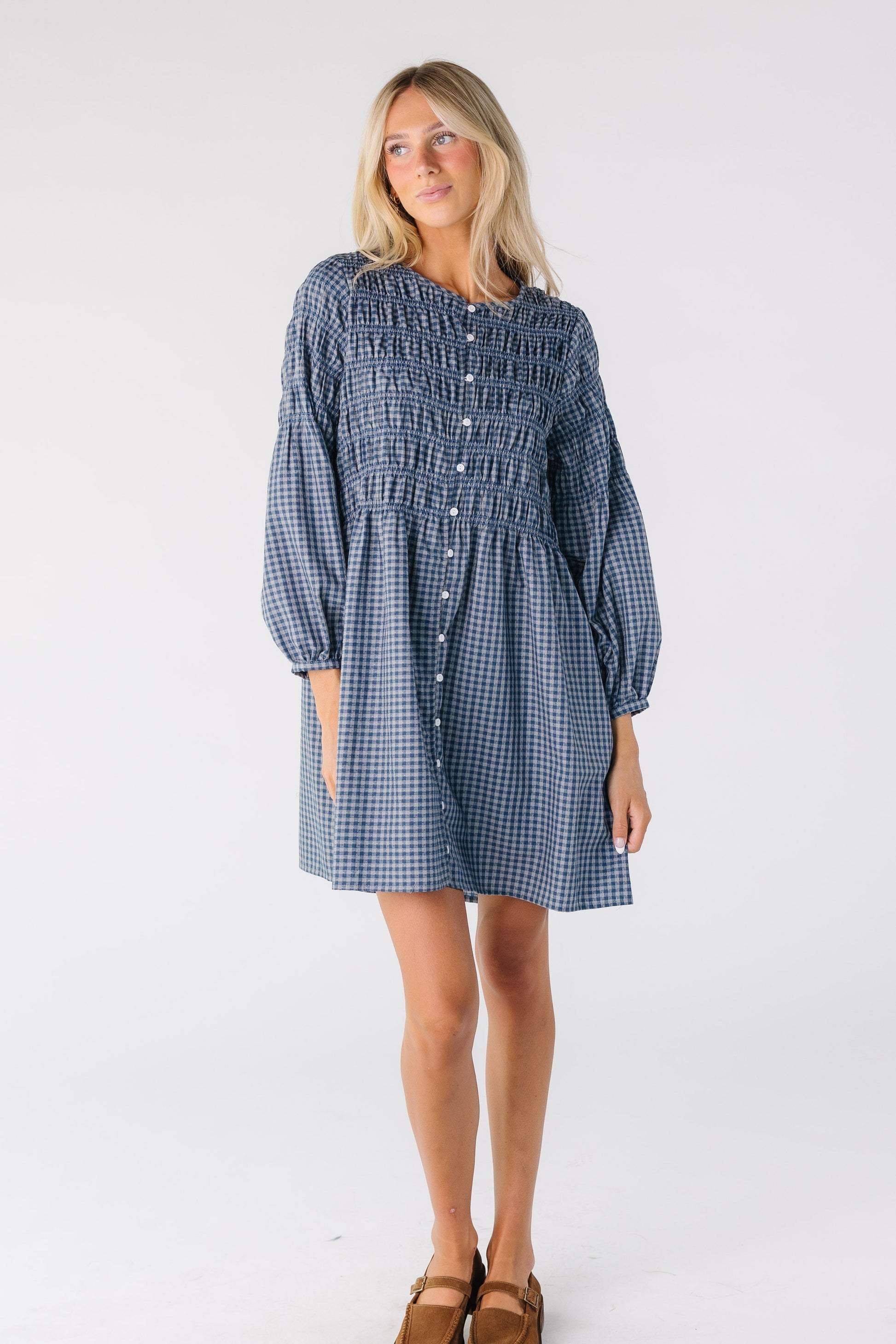 Woman wearing a blue gingham button down dresss with long sleeves