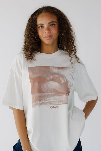 Teen girls wearing an oversize light cream tee with a large front graphic in brown with short sleeves.