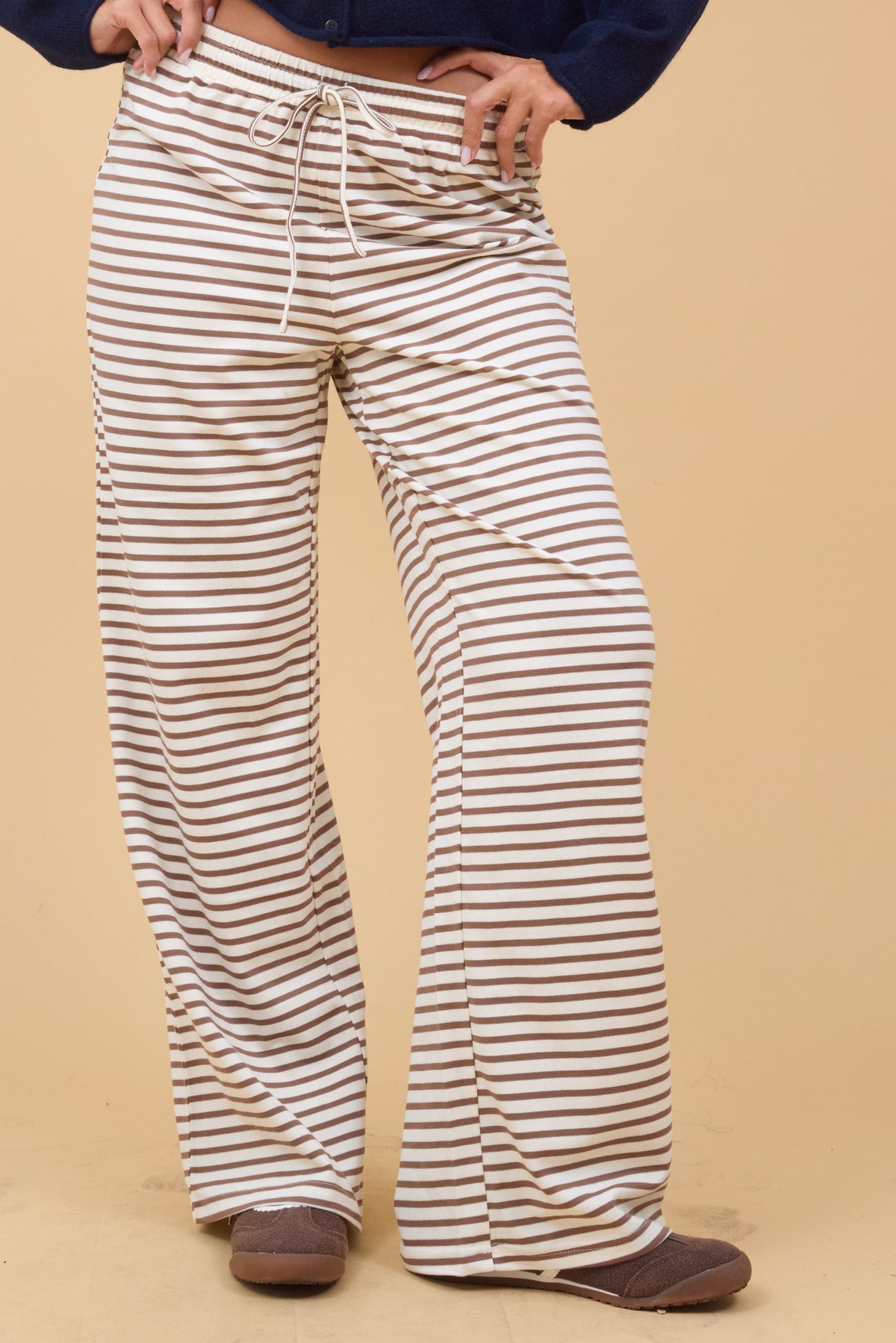 Young woman wearing modest cream & taupe stripe knit pants with a wide cut leg and elastic waist.