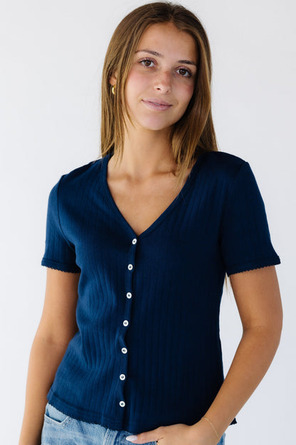 Young woman wearing a soft navy knit button down top with a V-neckline and short  sleeves.
