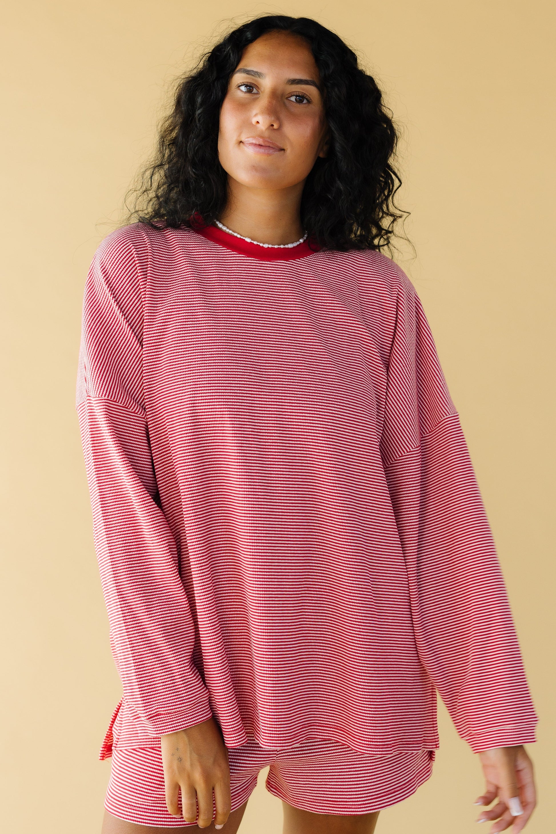 Young woman wearing a modest red & white stripe , very loose fitting top with long sleeves and a crew neckline.